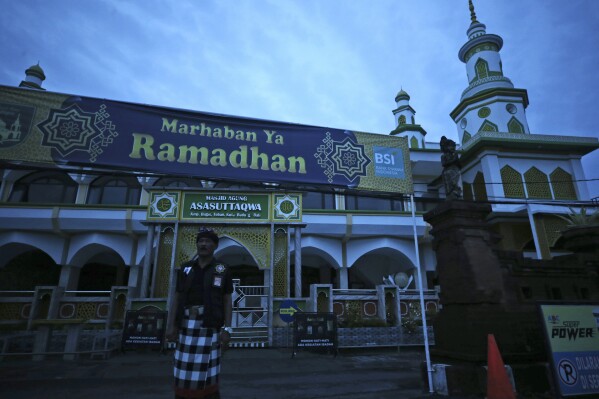 A Balinese traditional guard called "pecalang" stands outside a mosque on Nyepi, or Day of Silence, which also coincided with the first day of ramadan in Bali, Indonesia on Monday, March 11, 2024. Airports closed for 24 hours, the internet was turned off and streets were empty as the predominantly Hindu island of Bali in Muslim-majority Indonesia marked its New Year with an annual Day of Silence, part of six days of extensive New Year rituals. (AP Photo/Firdia Lisnawati)