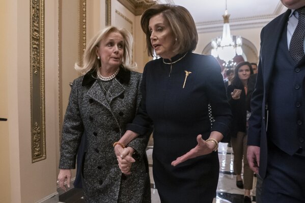 Speaker of the House Nancy Pelosi, D-Calif., holds hands with Rep. Debbie Dingell, D-Mich., left, as they walk to the chamber where the Democratic-controlled House of Representatives begins a day of debate on the impeachments charges against President Donald Trump for abuse of power and obstruction of Congress, at the Capitol in Washington, Wednesday, Dec. 18, 2019. (AP Photo/J. Scott Applewhite)
