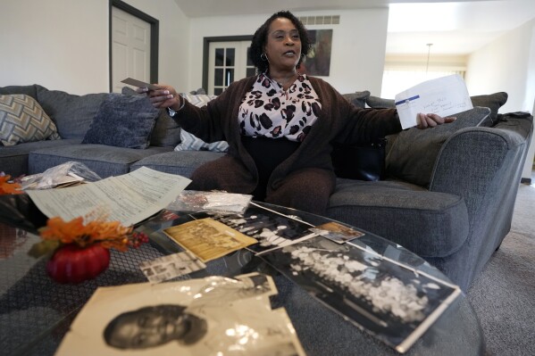 Tracy Brooks, an auto worker retiree is interviewed as she shows off vintage photos of her family, Wednesday, Oct. 18, 2023, in Romulus, Mich. She and her father, and grandfather and daughter all worked on assembly lines for one or more of Detroit's automakers. "We told Britney Johnson (Brooks' daughter), she's representing our family," Brooks jokes when speaking of her daughter who is among tens of thousands of the union's Ford, General Motors and Stellantis employees who have walked off the job since the strike started Sept. 15. (AP Photo/Carlos Osorio)