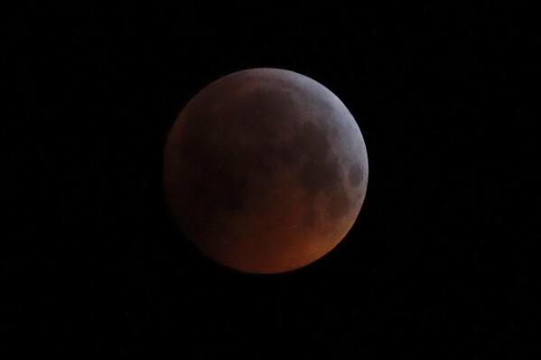 FILE - In this Monday, Jan. 21, 2019 file photo, the Earth's shadow falls across the full moon seen above Brighton, southeast England. The first total lunar eclipse in more than two years coincides with a supermoon this week for a cosmic show. This super “blood” moon will be visible Wednesday, May 26, 2021 across the Pacific _ offering the best viewing _ as well as the western half of North America, bottom of South America and eastern Asia. (AP Photo/Alastair Grant, File)