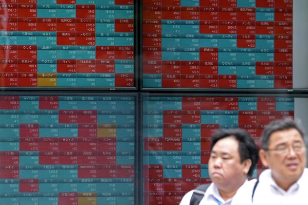FILE - People move past an electronic stock board showing Japan's stock prices outside a securities firm in Tokyo, June 7, 2024. Asian shares were mixed in muted trading Friday, June 14, after Wall Street’s continued frenzy around artificial-intelligence technology nudged indexes on Wall Street to more records.(AP Photo/Shuji Kajiyama, File)