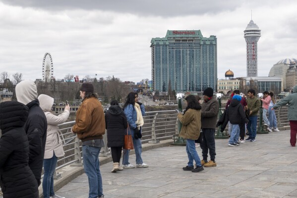Tourists on the American side of Niagara Falls take photos in Niagara Falls, N.Y. on Friday, March 29, 2024. Ontario's Niagara Region has declared a state of emergency as it readies to welcome up to a million visitors for the solar eclipse on April 8. (Carlos Osorio/The Canadian Press via AP)