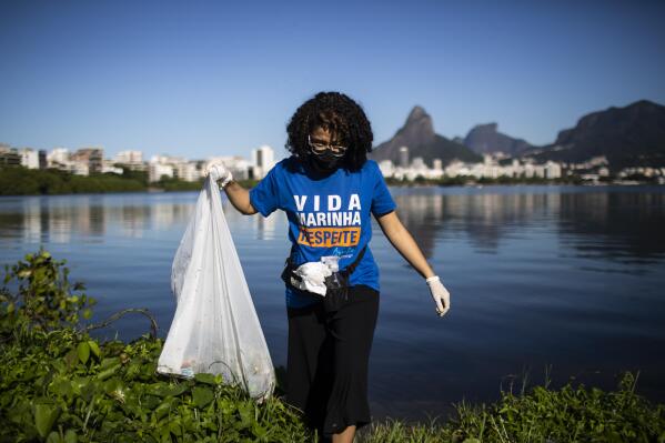 A volunteer collects garbage from the banks of the Rodrigo de Freitas Lagoon marking World Environment Day, in Rio de Janeiro, Brazil, Saturday, June 5, 2021. (AP Photo/Bruna Prado)
