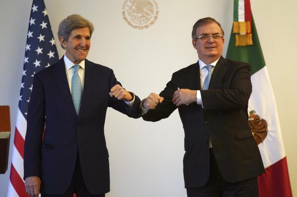 U.S. climate envoy John Kerry, left, bumps elbows with Mexican Foreign Minister Marcelo Ebrard during a photo opportunity on the sidelines of a meeting in Mexico City, Wednesday, Feb. 9, 2022.  Kerry arrived for talks amid high tensions over Mexico’s plan to favor its state-owned electricity company and limit private and foreign firms that have invested in renewable energy. (AP Photo/Fernando Llano)