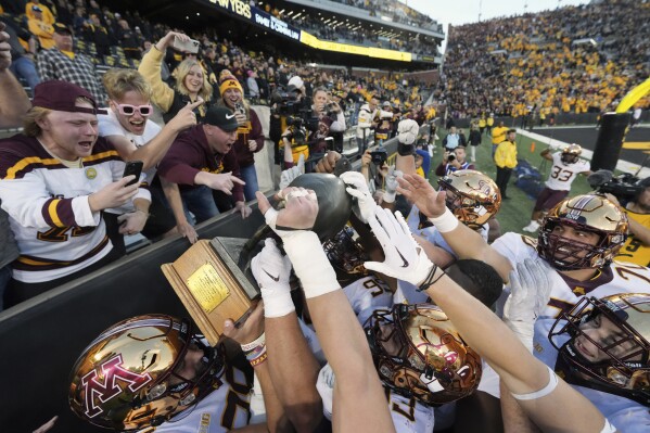 Minnesota hoists the Floyd of Rosedale trophy to the fans after their 12-10 win over Iowa in a NCAA college football game, Saturday, Oct. 21, 2023, in Iowa City, Iowa. (AP Photo/Matthew Putney)