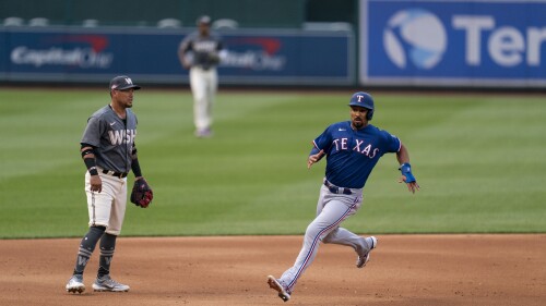 Texas Rangers' Marcus Semien runs toward third base on a double by Corey Seager, past Washington Nationals third baseman Ildemaro Vargas during the inning of a baseball game at Nationals Park, Friday, July 7, 2023, in Washington. (AP Photo/Stephanie Scarbrough)