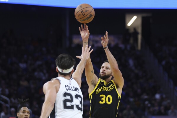 Golden State Warriors guard Stephen Curry (30) shoots against San Antonio Spurs forward Zach Collins (23) during the first half of an NBA basketball In-Season Tournament game in San Francisco, Friday, Nov. 24, 2023. (AP Photo/Jed Jacobsohn)