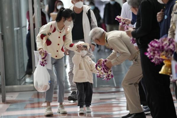 A Thai official gives a garland to Chinese tourists as they arrive at Suvarnabhumi International Airport in Samut Prakarn province, Thailand, Monday, Jan. 9, 2023. Thailand is looking forward to hosting visitors from China again after Beijing eased travel restrictions on Sunday. (AP Photo/Sakchai Lalit)