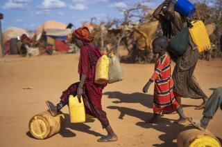 FILE - A Somali woman and children carry water at a camp for displaced people on the outskirts of Dollow, Somalia on Tuesday, Sept. 20, 2022. Madeleine Diouf Sarr, the chair of an influential negotiating bloc in the upcoming United Nations climate summit in Egypt has called for compensation for poorer countries suffering from climate change to be high up on the agenda. Sarr added that the bloc will push for funds to help developing countries adapt to droughts, floods and other climate-related events as well as urging developed nations to speed up their plans to reduce emissions.  (AP Photo/Jerome Delay, File)