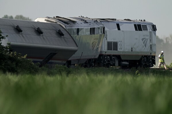FILE - A worker inspects the scene of an Amtrak train that derailed after striking a dump truck, June 27, 2022, near Mendon, Mo. The poor design of a rural Missouri railroad crossing contributed to the fatal Amtrak derailment in 2022 that killed four people and injured 146 others, the National Transportation Safety Board said Wednesday, Aug. 2, 2023. (AP Photo/Charlie Riedel, File)