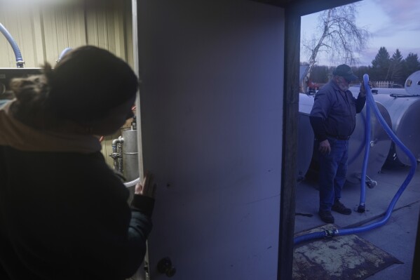 Dave Solin, right, holds a hose as his granddaughter, Ella, left, runs a reverse osmosis machine used for processing maple syrup, Sunday, Feb. 25, 2024, in Deerbrook, Wis. (AP Photo/Joshua A. Bickel)