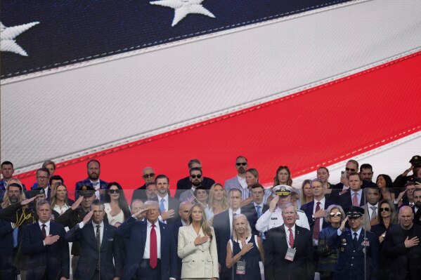 President Donald Trump, first lady Melania Trump, and other guests stand for the National Anthem, during a military parade commemorating the Army's 250th anniversary, coinciding with his 79th birthday, Saturday, June 14, 2025, in Washington. (AP Photo/Julia Demaree Nikhinson)