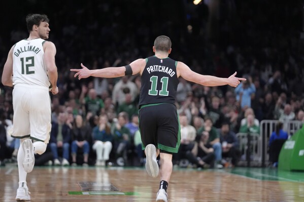 Boston Celtics guard Payton Pritchard (11) celebrates after scoring, next to Milwaukee Bucks forward Danilo Gallinari (12) during the first half of an NBA basketball game Wednesday, March 20, 2024, in Boston. (AP Photo/Steven Senne)