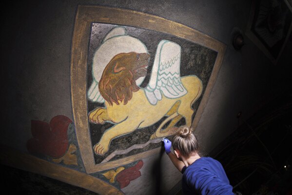 Art conservation technician Christina Cichra works on touching up a lion, symbol of the Gospel of St. Mark, in a mural by Maxo Vanka inside St. Nicholas Croatian Catholic Church in Millvale, Pa., Feb 13, 2025. (AP Photo/Gene J. Puskar)