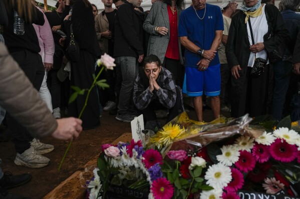 Mourners gather around the grave of Israeli reserve soldier Master Sgt. Raz Abulafia during his funeral in the village of Rishpon, Israel, Tuesday, Nov. 14, 2023. Abulafia, 27, was killed during a military ground operation in the Gaza Strip. (AP Photo/Ariel Schalit)