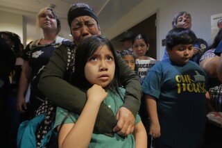 A woman embraces her child outside a House hearing room during protests against a bill that would allow public and charter schools to deny immigrant students from enrolling for classes in Nashville, Tenn., March 11, 2025. (AP Photo/George Walker IV, File)