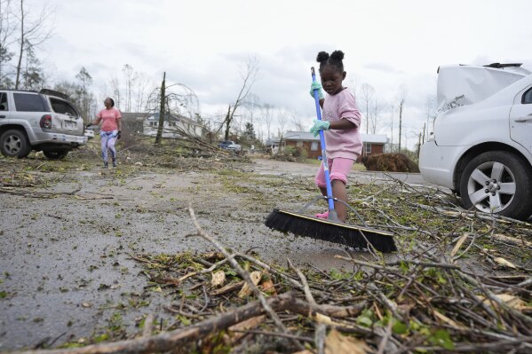 Azlin Douglas, 6, sweeps debris following severe weather in Selmer, Tenn., Thursday, April 3, 2025. (AP Photo/George Walker IV)
