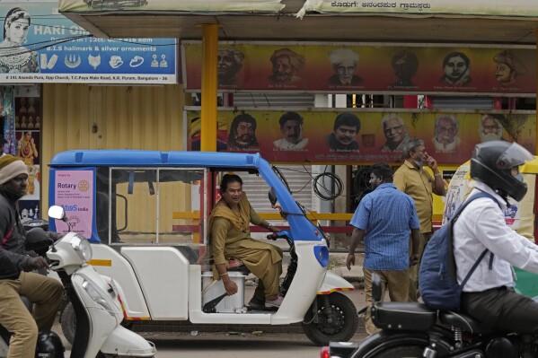 Preethi, a 38-year-old transgender woman who uses only her first name, parks her electric auto rickshaw next to a bus stop to look for passengers in Bengaluru, India, Wednesday, July 12, 2023.  (AP Photo/Aijaz Rahi)