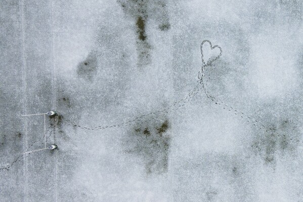 Footprints create the shape of a heart in a snow-covered rugby field in Santiago, Chile, May 8, 2024. (AP Photo/Matias Basualdo)