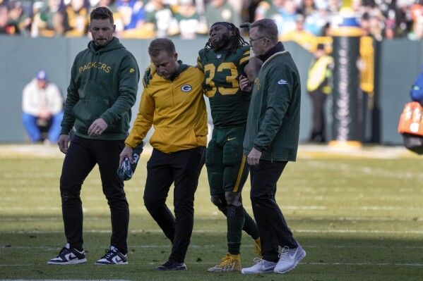 Green Bay Packers running back Aaron Jones (33) is walked off the field by trainers during the first half of an NFL football game against the Los Angeles Chargers, Sunday, Nov. 19, 2023, in Green Bay, Wis. (AP Photo/Morry Gash)