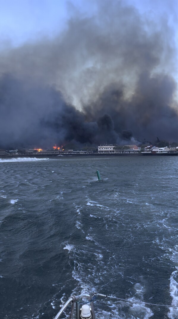 In this photo provided by Brantin Stevens smoke fill the air from wild fires at Lahaina harbor on Tuesday, Aug. 8, 2023 in Hawaii. Fire was widespread in Lahaina Town, including on Front Street, a popular shopping and dining area, County of Maui spokesperson Mahina Martin said by phone early Wednesday. Traffic has been very heavy as people try to evacuate the area, and officials asked people who weren’t in an evacuation area to shelter in place to avoid adding to the traffic, she said. (Brantin Stevens via AP)