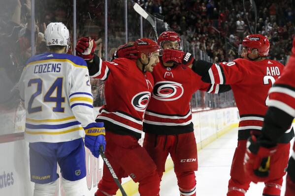Carolina Hurricanes' Nino Niederreiter (21) celebrates his goal with teammates Jalen Chatfield (64), and Sebastian Aho (20) as Buffalo Sabres' Dylan Cozens (24) skates by during the second period of an NHL hockey game in Raleigh, N.C., Saturday, Dec. 4, 2021. (AP Photo/Karl B DeBlaker)
