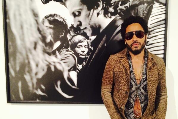 FILE - In this image taken from video, Musician Lenny Kravitz stands in front of one of his photos from his exhibit "Flash", which is running in conjunction with Art Basel in Miami Beach, Wednesday, Dec. 2, 2015.  Kravitz gave a private performance, Friday, Dec. 3, 2021,  for a star-studded crowd that included Leonardo DiCaprio and local Latin boy band CNCO during Miami’s Art week. (AP Photo/Joshua Replogle, File)