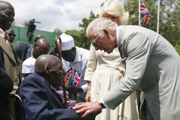 Britain's King Charles III, right, meets veteran Samwel Nthigai Mburia, who is believed to be 117 years old, during a visit to Kariokor World War II Commonwealth Cemetery in Nairobi, Kenya, Wednesday, Nov. 1, 2023. King Charles III has visited a war cemetery in Kenya, laying a wreath in honor of Kenyans who fought alongside the British in the two world wars. It came a day after the British monarch expressed “greatest sorrow and the deepest regret” for the violence of the colonial era. He gave replacement medals to four war veterans. (Victoria Jones/PA via AP)