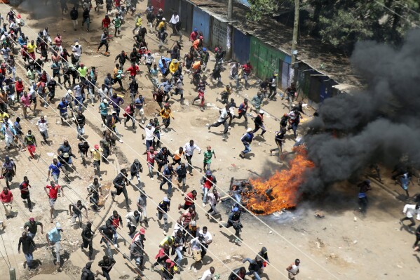 Protesters run towards riot police officers during a mass rally called by the opposition leader Raila Odinga over the high cost of living in Kibera Slums, Nairobi, Monday, March 27, 2023.(AP Photo/Brian Inganga)