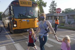 Sandra Young arrives at Whittier Elementary School with her daughters Baylin, 5, and Paytin, 2, on Tuesday, Aug. 24, 2021, in Salt Lake City. Kids in Salt Lake City are headed back to school Tuesday wearing masks after the mayor issued a mandate order despite heavy restrictions on mask mandates imposed by the GOP-dominated Legislature. (AP Photo/Rick Bowmer)
