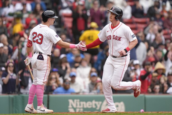 Boston Red Sox's Garrett Cooper, right, is welcomed at home by Romy Gonzalez, left, as he scores on a two-run ground rule double by Ceddanne Rafaela in the second inning of a baseball game against the Washington Nationals, Sunday, May 12, 2024, in Boston. (AP Photo/Steven Senne)