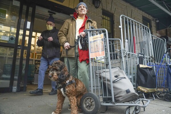 Aron Halberstam, right, and his dog Ralph leave after shopping at Brooklyn's Park Slope Co-Op grocery store, where a policy requires shoppers to mask-up Wednesdays and Thursdays, Thursday Dec. 7, 2023, in New York. (AP Photo/Bebeto Matthews)