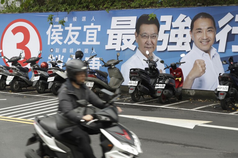 People pass by a poster of candidates running for the Taiwanese presidential election in Taipei, Taiwan, Saturday, Dec. 30, 2023. (AP Photo/Chiang Ying-ying, File)