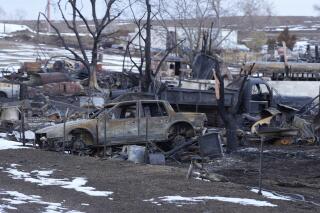 FILE - Charred vehicles sit amid the remains of a home, Jan. 14, 2022, in Superior, Colo., the area being searched for a 91-year-old woman missing since a wildfire burned over 1,000 homes and buildings in suburban Denver last month. Authorities said Wednesday, Jan. 19, 2022, that they have found small bone fragments in their search for Edna Nadine Turnbull but were still investigating whether they were human or not. (AP Photo/David Zalubowski, File)