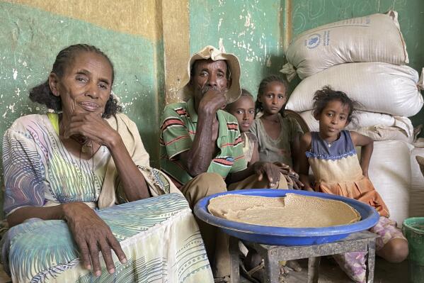Tesfay, center, sits with his wife and grandchildren, who have been displaced for 18 months, as they receive food assistance for the first time in 8 months from the World Food Programme (WFP), in the town of Adi Mehameday, in the western Tigray region of Ethiopia, Saturday, May 28, 2022. Hunger is tightening its grip on millions of people in Ethiopia who are facing a combination of conflict in the north and drought in the south while dwindling resources mean food and nutrition support may run dry from next month, the World Food Programme (WFP) warned Thursday, June 23, 2022. (Claire Nevill/WFP via AP)