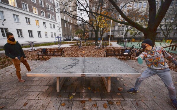 Two men play table tennis in a city square in Warsaw, Poland, Saturday, Nov. 7, 2020. Due to the increase in coronavirus cases, the government introduced new restrictions in shops, schools and cultural institutions through November. (AP Photo/Czarek Sokolowski)