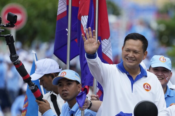 Hun Manet, front right, a son of Cambodia Prime Minister Hun Sen, waves from a vehicle as he leads a procession to mark the end of an election campaign of Cambodian People's Party, in Phnom Penh, Cambodia, Friday, July 21, 2023. Hun Sen says he is ready to hand the premiership to his oldest son, Hun Manet, who heads the country’s army. (AP Photo/Heng Sinith)