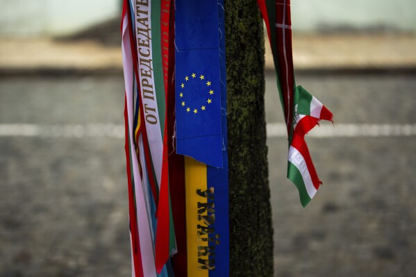 Ribbons in the colors of the European Union and Ukraine are tied to a tree next to the memorial wall for Ukrainian soldiers killed during the war in kyiv, Ukraine, Monday, April 22, 2024. (AP Photo/Francisco Seco)