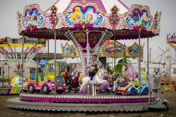 A woman rests on a merry-go-round while waiting for customers during rainfall at a fair in Hagioaica, Romania, Saturday, Sept. 16, 2023. For many families in poorer areas of the country, Romania's autumn fairs, like the Titu Fair, are one of the very few still affordable entertainment events of the year. (AP Photo/Vadim Ghirda)