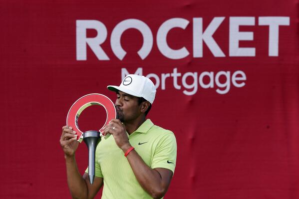 Tony Finau kisses the winner's trophy after the final round of the Rocket Mortgage Classic golf tournament, Sunday, July 31, 2022, in Detroit. (AP Photo/Carlos Osorio)