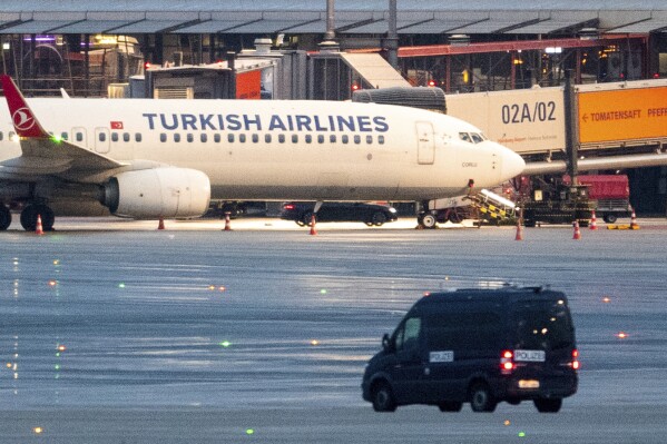 05 November 2023, Hamburg: A police vehicle is parked in front of an airplane at the airport, where a car with a hostage-taker is parked, in Hamburg, Germany, Sunday, Nov. 5, 2023. An armed man is holding his four-year-old daughter at the airport. According to the police, the background to the attack is a custody dispute.(Daniel Bockwoldt/dpa via AP)