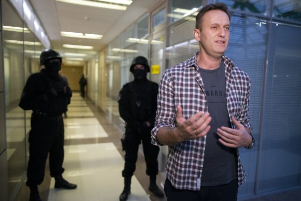 Russian opposition leader Alexei Navalny speaks to the media as policemуn stand guard at the Foundation for Fighting Corruption office in Moscow, Russia, Thursday, Dec. 26, 2019. Alexei Navalny, the most prominent foe of President Vladimir Putin and the governing United Russia party was detained in his office in Moscow. (AP Photo/Alexander Zemlianichenko)
