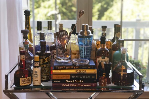 A collection of spirits and cocktail recipe books are displayed at a home in Alexandria, Va., on Oct. 4, 2020. Since the pandemic hit the United States, a lot of social drinking has moved back home. (Elizabeth Karmel via AP)