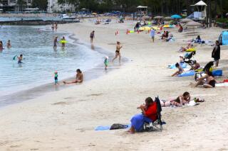 FILE — In this Aug. 24, 2021, file photo people sit on Waikiki Beach in Honolulu. Hawaii's COVID-19 case counts and hospitalizations have declined to the point where the islands are ready to welcome travelers once again, the governor said Tuesday, Oct. 19. (AP Photo/Caleb Jones, File)
