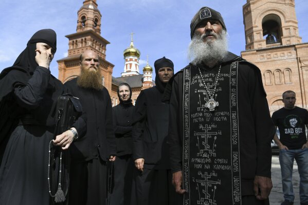 FILE In this file photo taken on Wednesday, June 17, 2020, Father Sergiy, a Russian monk who has defied the Russian Orthodox Church's leadership, right, speaks to journalists in Russian Ural's Sredneuralsk, Russia. The Russian Orthodox Church on Friday July 3, 2020, defrocked Father Sergiy, who has defied the coronavirus lockdown orders and has taken control over a monastery. (AP Photo/Vladimir Podoksyonov, FILE)