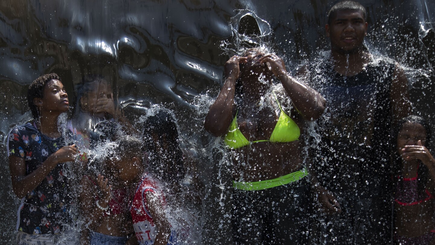 People cool off in a water fountain at Madureira Park amid a heat wave in Rio de Janeiro, Brazil, Wednesday, Nov. 15, 2023. (AP Photo/Bruna Prado) A y