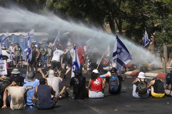 Israeli police use water cannon to disperse demonstrators blocking the road leading to the Knesset, Israel's parliament, during a protest against plans by Prime Minister Benjamin Netanyahu's government to overhaul the judicial system, in Jerusalem, Monday, July 24, 2023. The demonstration came hours before parliament is expected to vote on a key part of the plan. (AP Photo/Mahmoud Illean)
