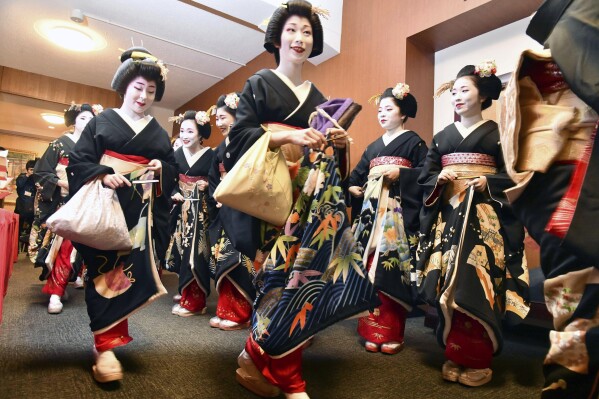 FILE - Kimono-clad "geiko" and "maiko" professional entertainers arrive for a ceremony to start this year's business in Kyoto, western Japan, on Jan. 7, 2020. Japan’s ancient capital of Kyoto, long a popular destination for tourists, will be closing off some private-property alleys in its famous geisha district, as complaints grow about misbehaving visitors. (Kyodo News via AP, File)