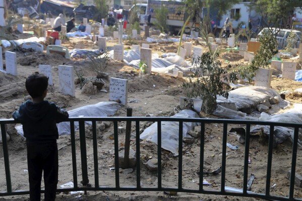 FILE - A Palestinian child looks at the graves of people killed in the Israeli bombardment of the Gaza Strip and buried inside the Shifa Hospital grounds in Gaza City, Sunday, Dec. 31, 2023. (AP Photo/Mohammed Hajjar, File)