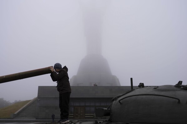 A boy plays on a tank installed as a monument in Kyiv, Ukraine, in front of the Motherland monument, just reopened for public viewing on Saturday, Oct. 21, 2023. (AP Photo/Alex Babenko)